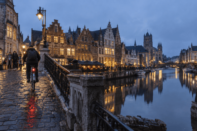 Cyclist beside the medieval canal quays of Ghent at blue hour