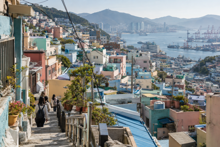 Pastel homes of Gamcheon Culture Village descending toward Busan’s working harbour in clear coastal light