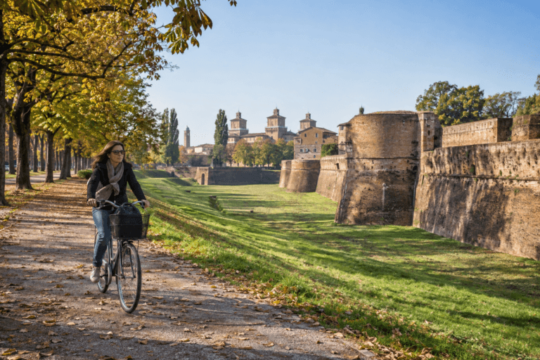 Photorealistic cyclist riding beside Ferrara’s historic brick walls in soft autumn morning light